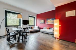 un soggiorno con parete rossa, tavolo e sedie di Music Bridge Apartment a Roma