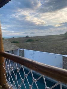 a balcony with a fence and a view of a field at Flor de Cacto Beach Home in São Miguel do Gostoso