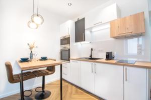 a kitchen with white cabinets and a wooden table at L'Appartement des Ducs avec Baignoire Double in Nantes