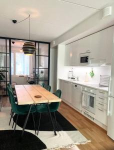 a kitchen and dining room with a wooden table and green chairs at JATKASAARI-2 - Chic and cosy Sea side stay in Helsinki
