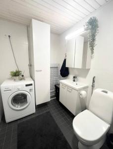 a white bathroom with a toilet and a washing machine at JATKASAARI-2 - Chic and cosy Sea side stay in Helsinki