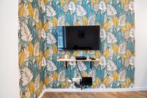 a tv on a wall with a colorful wallpaper at L'Appartement des Ducs avec Baignoire Double in Nantes