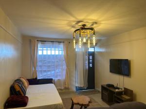 a room with a bed and a television and a chandelier at J L appartment in Eldoret