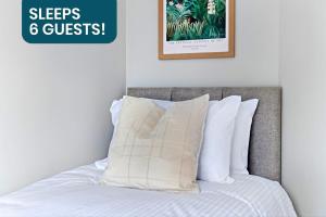 a bed with white pillows and a sign that reads sleeps guests at Spacious 3-bed House in Nottingham by Renzo, Amazing Location, Sleeps 6! in Nottingham