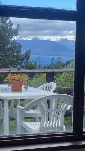 uma mesa branca e cadeiras numa varanda com vista em Otto House em San Carlos de Bariloche