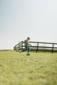 Ein kleiner Junge, der auf einem Feld auf einem Skateboard reitet. in der Unterkunft Büdlfarm - Der Familien-Erlebnishof in Strandnähe in Fehmarn