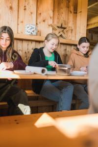 Büdlfarm - Der Familien-Erlebnishof in Strandnähe في فيهمارن: ثلاث فتيات جالسات على طاولة في مطعم