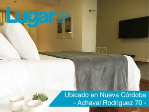 Habitación de hotel con cama y TV en Departamentos Lugar en Córdoba