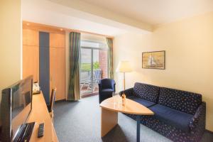 ein Wohnzimmer mit einem Sofa und einem Tisch in der Unterkunft Hotel Strandburg in Baltrum