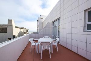 - Balcón con mesa blanca y sillas en On The Beach 19 - Sea View Apartment, en Swakopmund