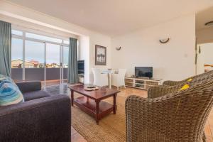 Una sala de estar con un sofá y sillas y una mesa. en On The Beach 19 - Sea View Apartment, en Swakopmund