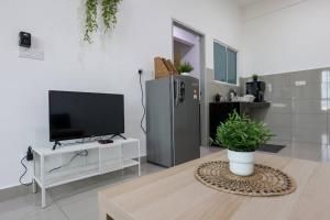 un soggiorno con TV e pianta in vaso di Amber Cove 2BR WIFI Kitchen New Unit 2 Bathroom a Malacca