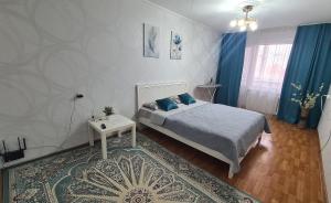 a bedroom with a bed and a table and a rug at 1 к квартира в Центре Мухита д 128 in Uralsk