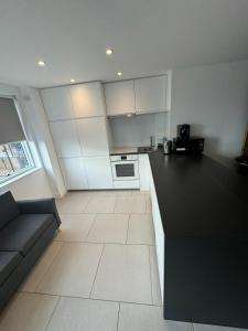 a kitchen with white cabinets and a black counter top at Two bed in Clapham in London