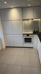 a kitchen with white cabinets and a tile floor at Two bed in Clapham in London