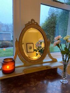 einen Spiegel im Fenster mit einer Vase und einer Kerze in der Unterkunft Cosy Wee Cottage St Andrews 20 in Ceres