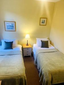 a room with two beds and a table with a lamp at Cosy Wee Cottage St Andrews 20 in Ceres