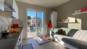 een woonkamer met een bank en een keuken bij La Casa Nuova - Pietra Ligure in Pietra Ligure