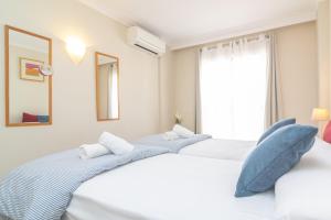 two beds in a white room with a window at Novi in Port d'Alcudia