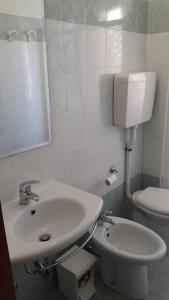een witte badkamer met een wastafel en een toilet bij Appartamento ROYAL in Gatteo a Mare