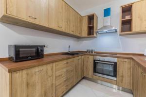 una cucina con armadi in legno e forno a microonde di Marsaxlokk Two Bedroom Apartment 1 minute away from the seafront a Marsaxlokk
