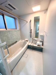 a white bathroom with a tub and a toilet at Shima Stay holoholo in Zamami +37 photos
