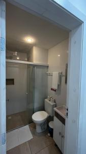 uma casa de banho com um WC e uma cabina de duche em vidro. em Pousada Pedras do Mariscal em Bombinhas