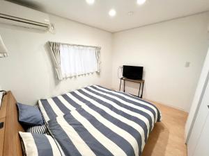 a bedroom with a striped bed and a television at Shima Stay holoholo in Zamami