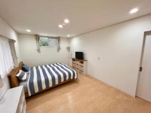 a bedroom with a bed and a television in it at Shima Stay holoholo in Zamami