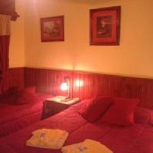 a bedroom with a red bed and a table with a lamp at Hotel El Nogal La Falda in La Falda