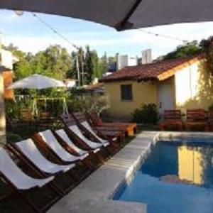 a swimming pool with lounge chairs and a house at Hotel El Nogal La Falda in La Falda