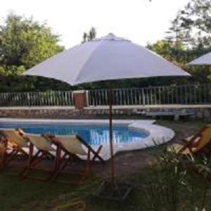 a white umbrella and chairs next to a pool at Hotel El Nogal La Falda in La Falda