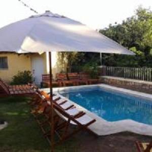 an umbrella and chairs next to a swimming pool at Hotel El Nogal La Falda in La Falda