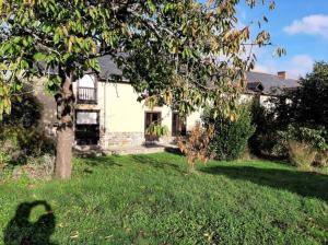 une maison blanche avec un arbre dans la cour dans l'établissement Longère familiale, à Melesse