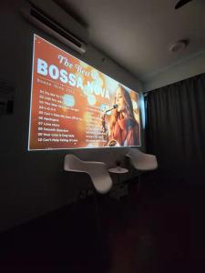 een groot scherm met een presentatie op een muur met stoelen bij Almas #28-13 - New Almas Suite Cozy in Nusajaya