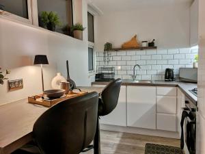 uma cozinha com armários brancos e uma mesa de madeira com cadeiras em Spacious and modern flat in Archway em Londres