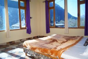 a bedroom with windows and a bed in a room at Apple Garden Katagla Kasol in Kasol