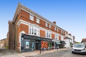 a red brick building with a store on a street at Ascot House Apartment in Hurstpierpoint