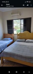 two beds in a room with two windows at Casa aconchegante próximo ao Rio Dourados in Dourados