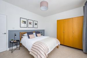 a bedroom with a bed and a wooden cabinet at Ascot House Apartment in Hurstpierpoint
