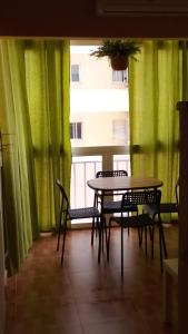una mesa y sillas en una habitación con cortinas verdes en Sueña Paco en Torremolinos