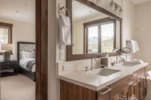 a bathroom with a sink and a mirror and a bed at Spanish Peaks | Highlands Cabin 30 in Big Sky +46 photos