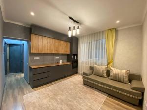 a living room with a couch and a kitchen at Apart 23 in Karakol