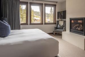 a bedroom with a large white bed and a fireplace at Spanish Peaks | Highlands Cabin 30 in Big Sky