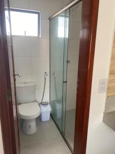 La salle de bains est pourvue de toilettes et d'une douche en verre. dans l'établissement Flor de Cacto Beach Home, à São Miguel do Gostoso