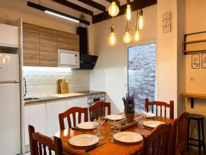 cocina con mesa de madera con sillas y nevera en Casa Rural La Travesía, en Bolulla