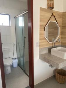 a bathroom with a toilet and a sink and a mirror at Flor de Cacto Beach Home in São Miguel do Gostoso