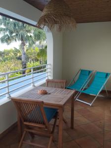 una mesa y sillas en una habitación con balcón en Les oliviers sous le cocotier en Saint-Joseph