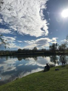 un hombre sentado en el césped junto a un lago en Apartmani Golubina - Trn, Laktasi, BANJA LUKA en Grabljani