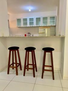 a kitchen with two bar stools in front of a counter at Flat Barra do Cunhaú in Canguaretama